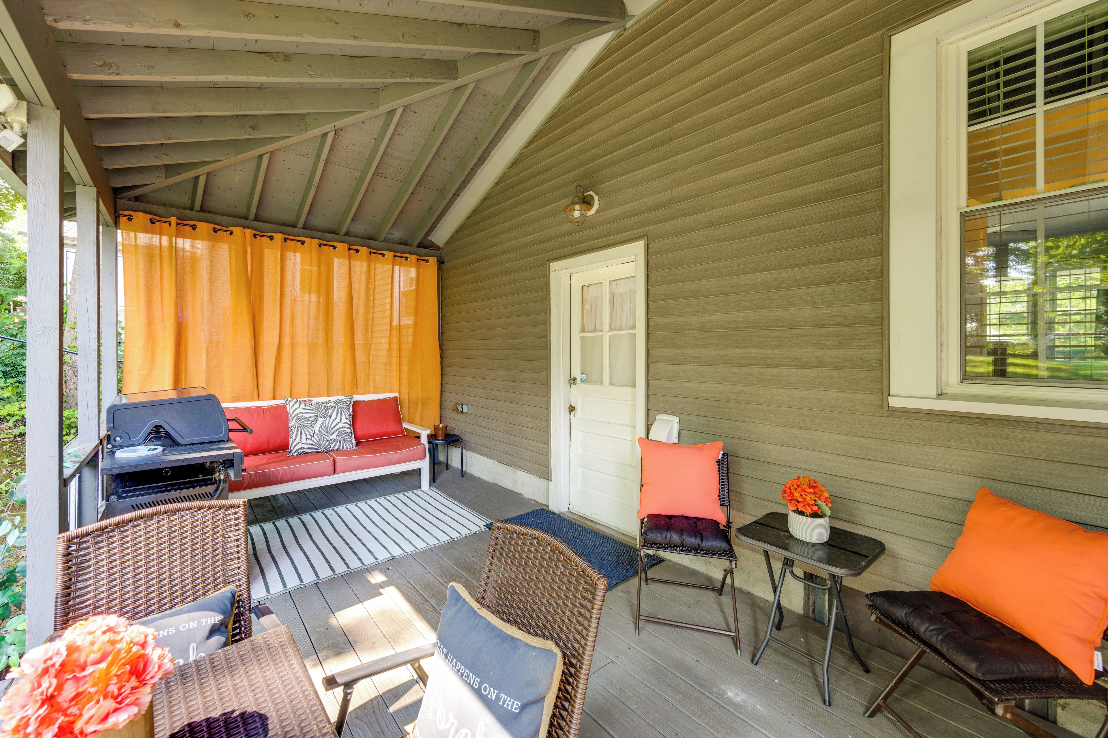 A covered porch with outdoor seating, a grill, and a door leading to the house.