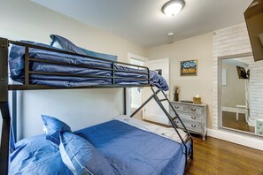 Una litera con escalera, un aparador y un cuadro en la pared.