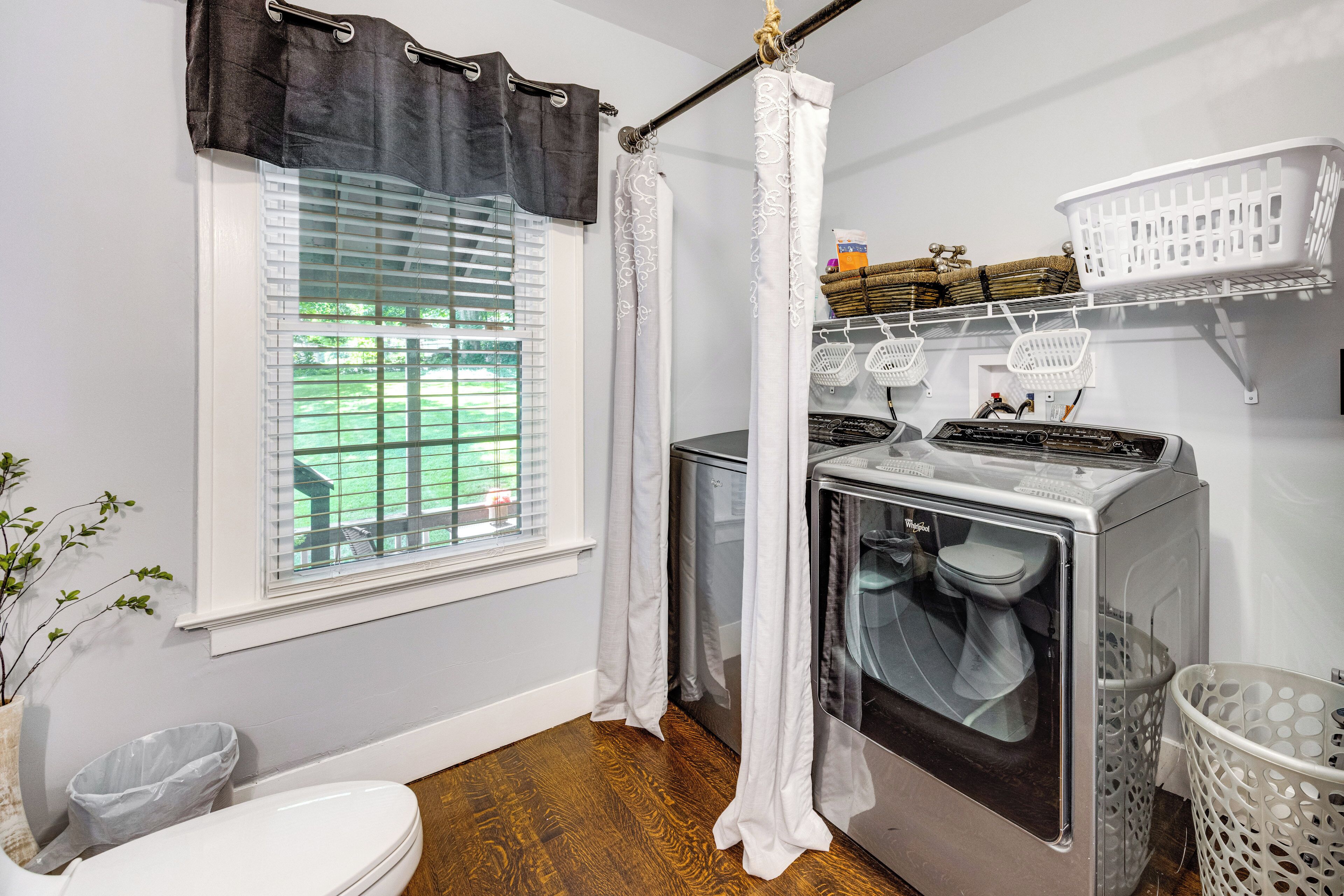 A laundry room with a washing machine, a dryer, and a window with blinds.