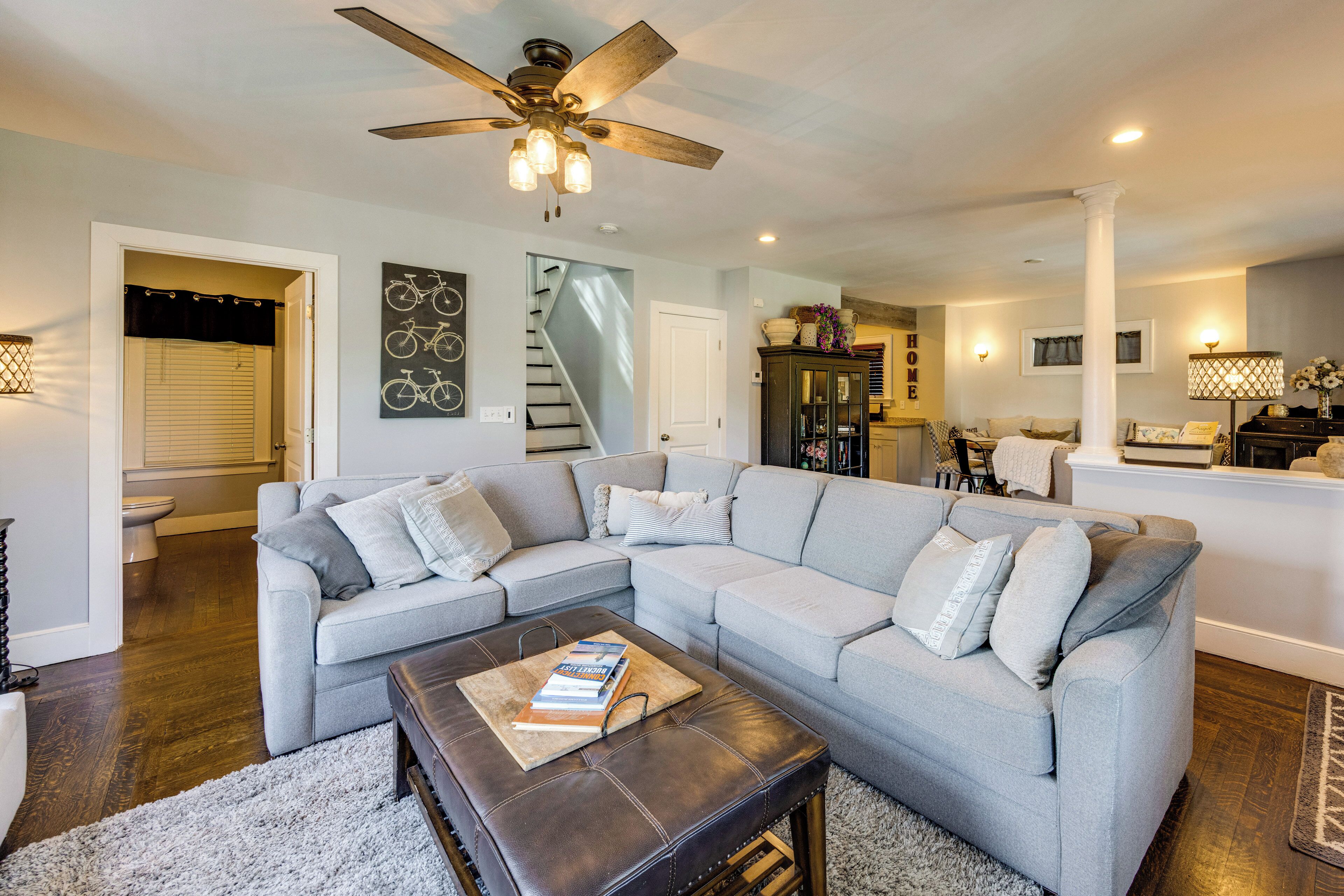 A modern living room with a sectional sofa, a coffee table, and a ceiling fan.