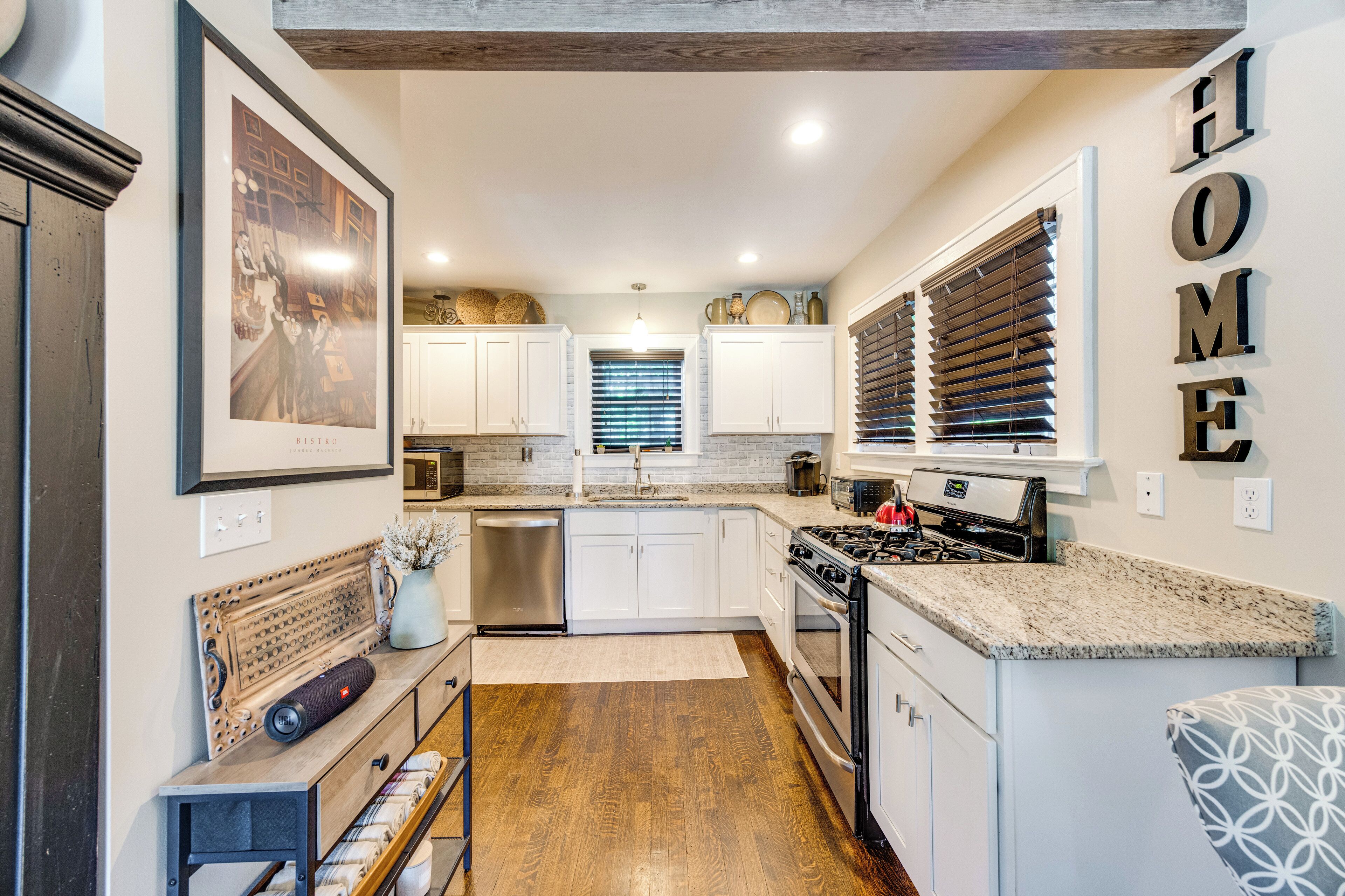 A modern kitchen with white cabinets, a stainless steel dishwasher, and a gas stove.