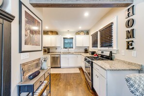 Una cocina moderna con armarios blancos, lavavajillas de acero inoxidable y cocina a gas.