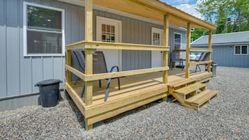 A wooden deck with a bench and a trash can.