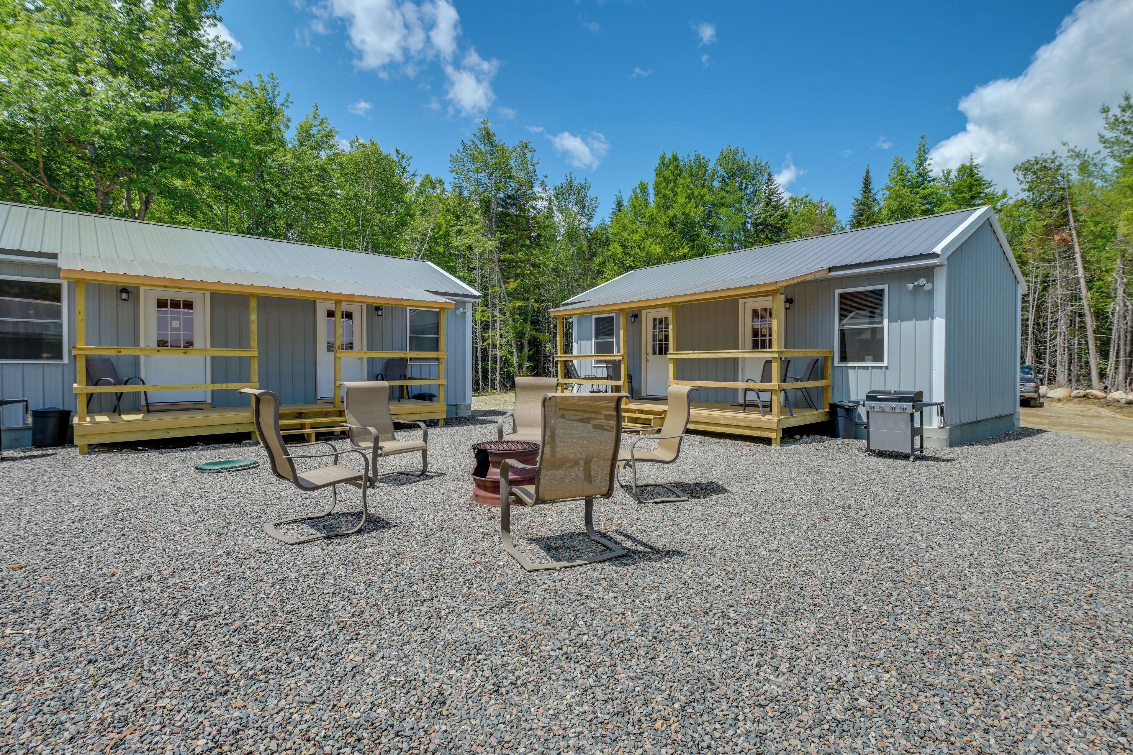 A campground with two cabins, each with a porch and outdoor seating.