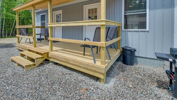 A wooden deck with outdoor seating, a gravel ground, and a building with a window and door. - Ride ATV Trails! Downeast Studio for Adventurers (Wesley)