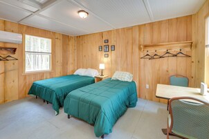 Una habitación con dos camas, una mesa, una silla y un ventanal.