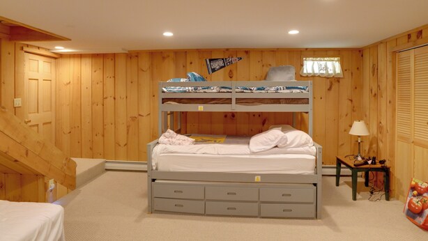 A bunk bed with storage drawers, a small bedside table with a lamp, and a window with curtains. - Deck & Wooded Views! Rural Windham Group Retreat (West Townshend)