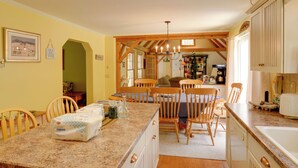 A kitchen with a granite countertop, wooden chairs, and a central island with a table. - Deck & Wooded Views! Rural Windham Group Retreat (West Townshend)