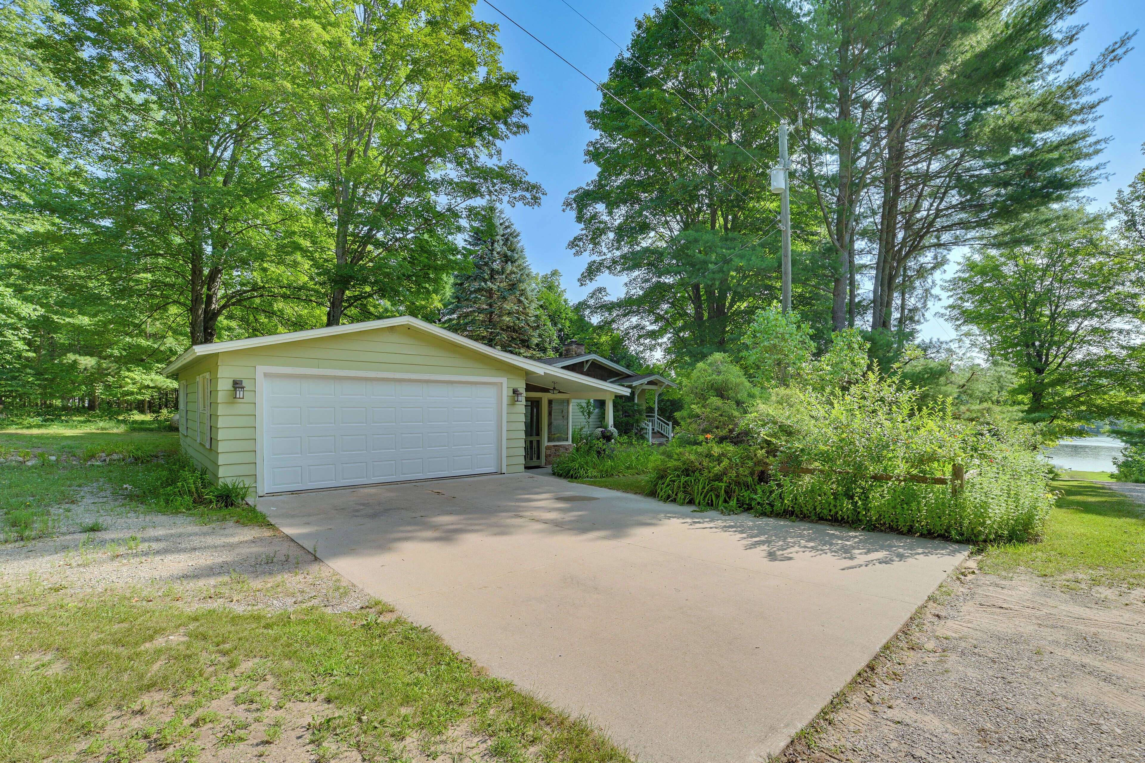 A single-story house with a garage, surrounded by dense greenery and trees.