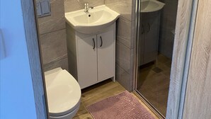 A bathroom with a toilet, a sink, and a shower area. - Comfortable 4-person Room With Kitchenette (Mielno)