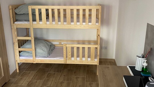 A bunk bed with a desk and chair, a small table with a laptop, and a wall socket. - Comfortable 4-person Room With Kitchenette (Mielno)