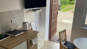 A modern kitchen with a flat-screen TV, a kettle, and a coffee machine on the counter. - Comfortable 4-person Room With Kitchenette (Mielno)
