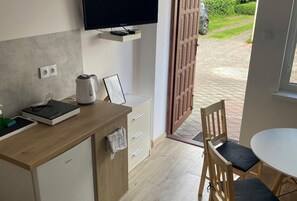A modern kitchen with a flat-screen TV, a kettle, and a coffee machine on the counter. - Comfortable 4-person Room With Kitchenette (Mielno)