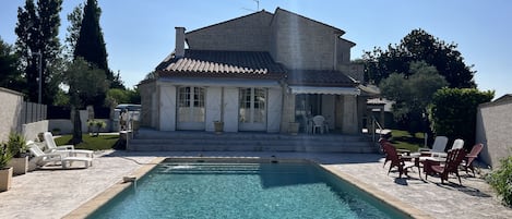 A house with a swimming pool, outdoor furniture, and a garden.