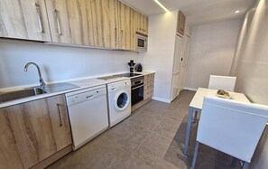 Una cocina funcional con lavadora, microondas y pileta.