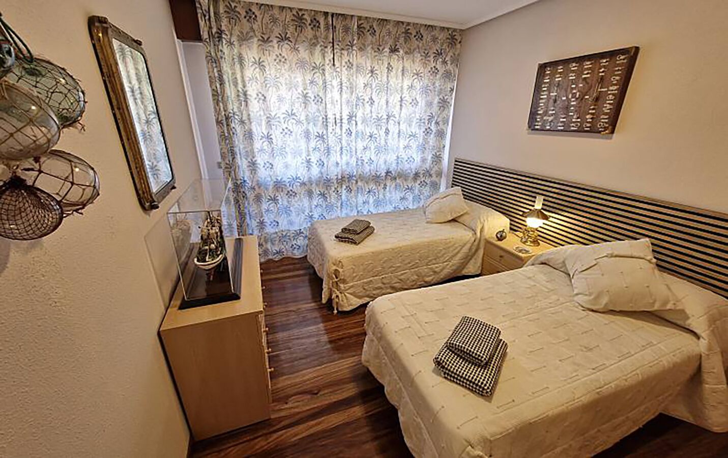 Habitación de hotel con dos camas, un escritorio pequeño y una ventana con cortinas.