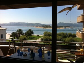 Una mesa con copas y botellas de vino, con vista a una playa y al mar.