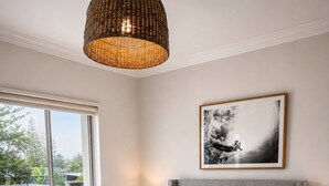 A bedroom with a bed, bedside tables, a lamp, a framed picture, and a large window. - Coastal Retreat, 2 Bedroom Apartment Near Tathra Beach (Tathra)