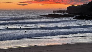 A beach with waves, a pier, and a building on a cliff. - Coastal Retreat, 2 Bedroom Apartment Near Tathra Beach (Tathra)