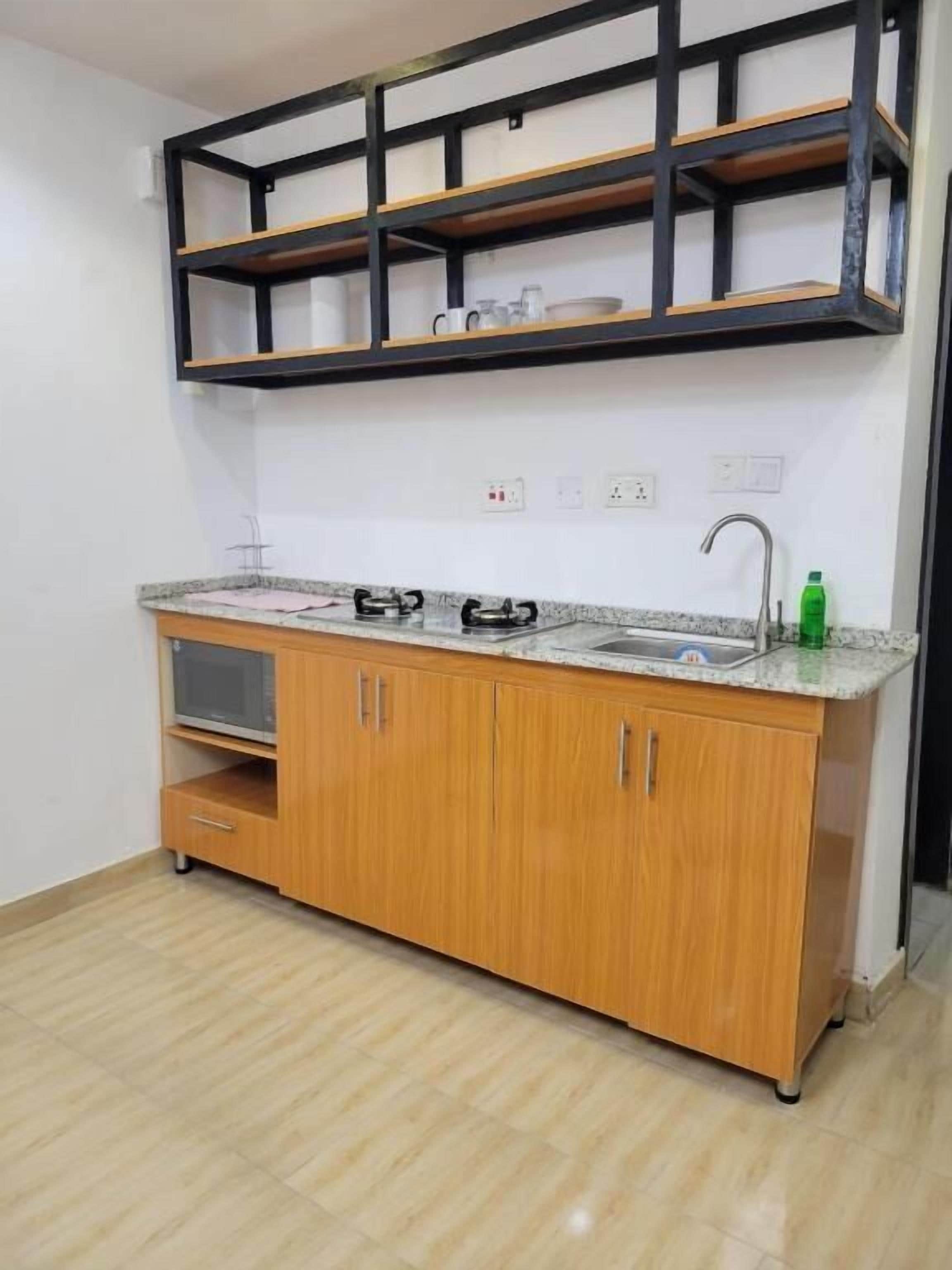 A kitchen with a countertop, cabinets, a sink, and a shelf above the countertop.