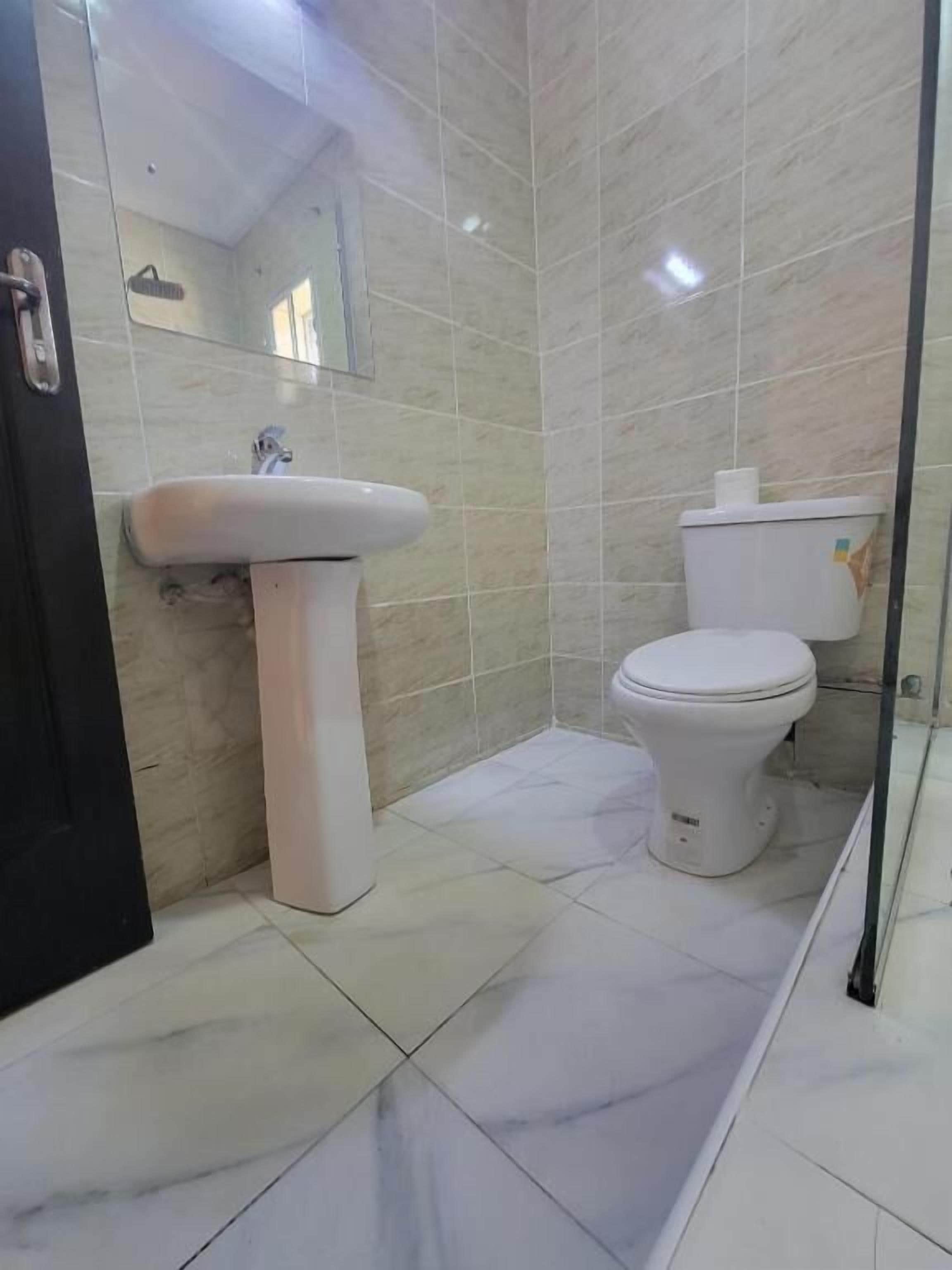 A bathroom with a white sink, toilet, and mirror.