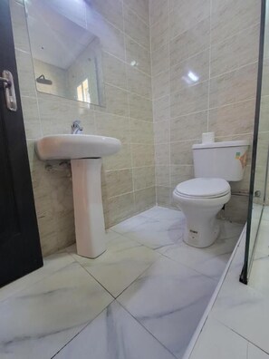 Un baño con lavamanos, inodoro y espejo blancos.