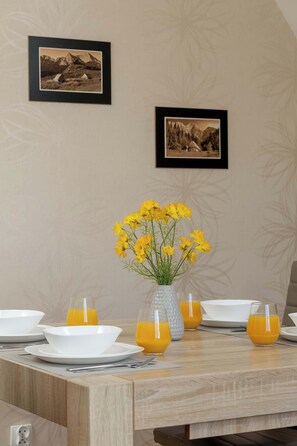 A dining table with plates, glasses, and a vase of yellow flowers.
