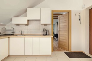 A modern kitchen with a central island, built-in cabinets, and a wooden door leading to another room.