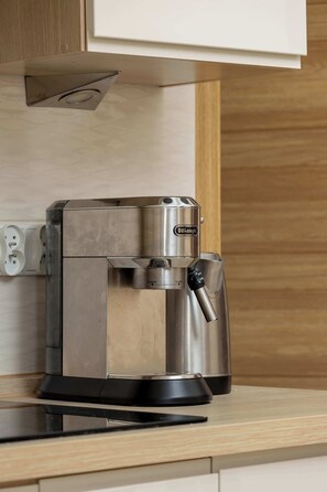 Una cafetera DeLonghi con bandeja de goteo sobre una encimera de cocina.