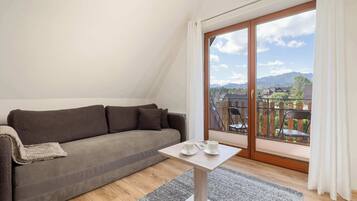 A modern living room with a sofa, a small table, and a view of a town through large windows.