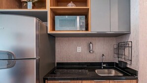 A compact kitchen with a refrigerator, microwave, sink, and wooden cabinets. - Studio in a Cond. With a Pool Near the sea Aru0123 (Salvador)