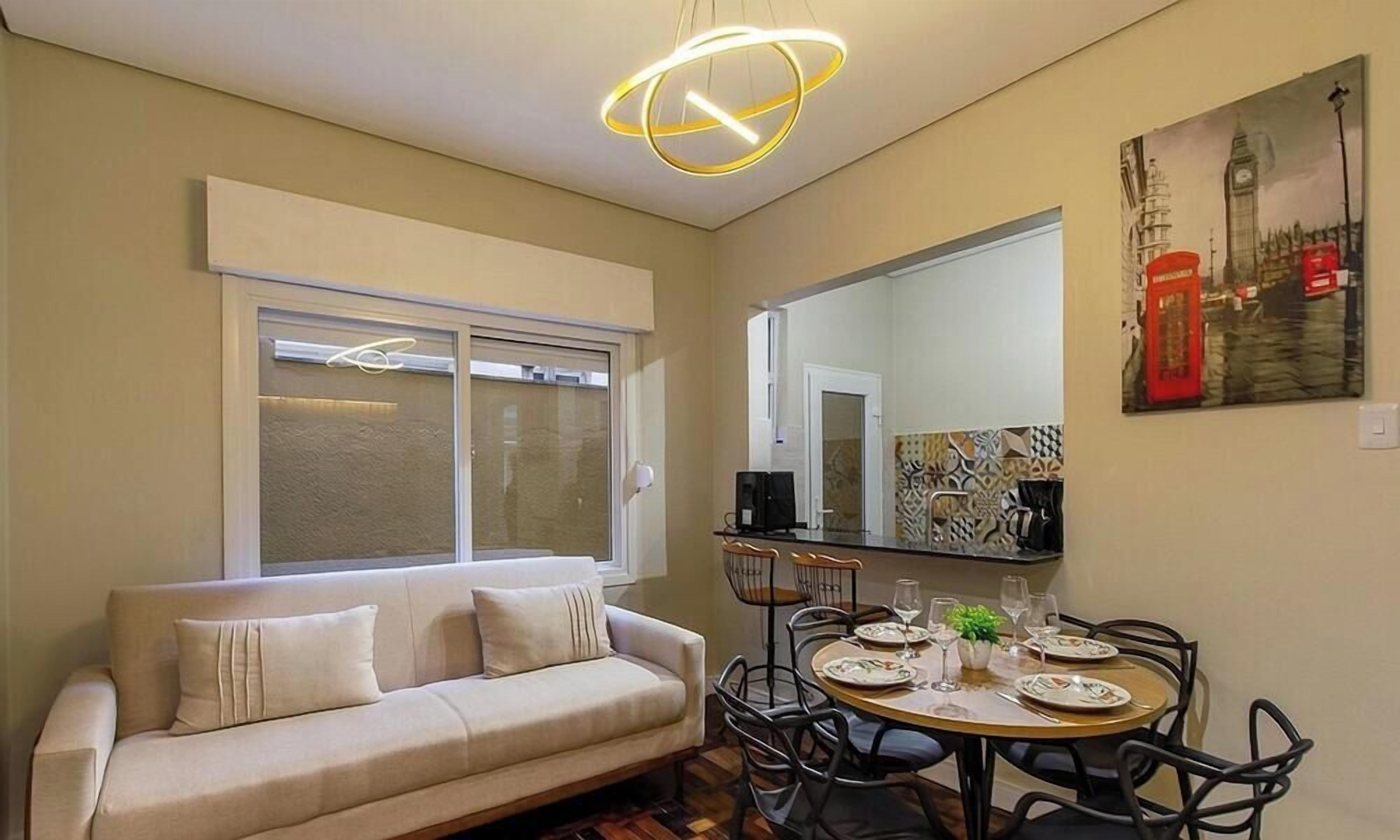 Uma sala de estar com sofá, mesa de jantar, cadeiras e um quadro de uma cabine telefônica vermelha.
