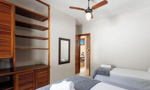 Ein Schlafzimmer mit zwei Betten, einem Holzschrank, einem Deckenventilator und einem Spiegel.