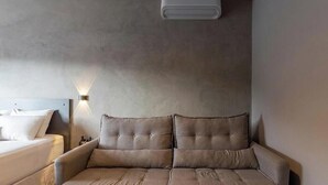 Un dormitorio moderno con una cama sofa, una mesita de noche, aire acondicionado de pared y una lámpara de pared.