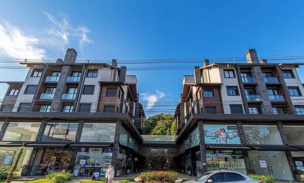 A modern building with multiple floors, large windows, and a central atrium. - Apt. w/ Fireplace & Balcony in Gramado Ohs0501 (Gramado)
