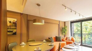A modern dining area with a round table, chairs, and a hanging light fixture. - Apt. w/ Fireplace & Balcony in Gramado Ohs0501 (Gramado)