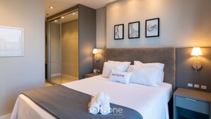 Een moderne hotelkamer met een bed, twee wandlampen, een nachtkastje en een spiegel.