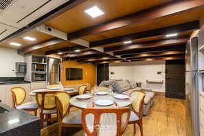 A compact kitchen with modern appliances, a dining area with a round table and chairs, and a cozy seating area with a sofa. - Comfort in Front of Befly Hall Sio0302 (Belo Horizonte)