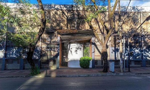 A building facade with a gated entrance, a small covered area, and a large white cylindrical structure. - Comfort in Front of Befly Hall Sio0302 (Belo Horizonte)
