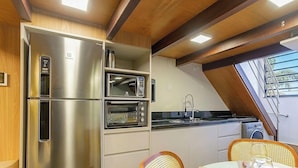 Eine kleine Küche mit Kühlschrank, Mikrowelle, Backofen und Spüle.