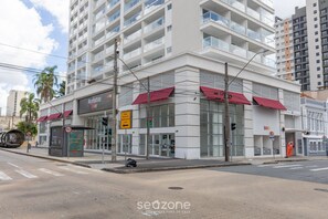 A modern building with a commercial ground floor, featuring a restaurant named "Manhattan Love" with red awnings, and a visible sign indicating a 40 km/h speed limit. - Sophisticated Studio in a Cond. With a gym Man1707 (Curitiba)