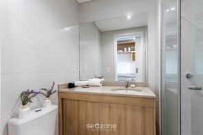 Ein modernes Badezimmer mit einem Holzwaschtisch, einem großen Spiegel und einer Duschkabine aus Glas.