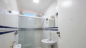 Un bagno con box doccia in vetro, lavandino bianco e specchio sopra.
