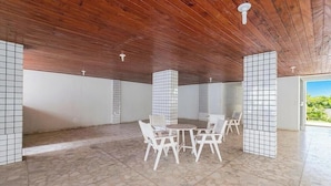 Una stanza spaziosa con soffitto in legno, pareti piastrellate e pavimento in pietra. Al centro, un tavolo rotondo con sedie.