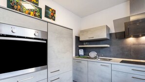 Een moderne keuken met roestvrijstalen apparatuur, grijze keukenkastjes en een zwarte afzuigkap.