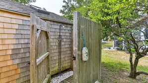 A wooden structure with a door and a small step leading to a gravel path. - Cozy pet-friendly 1-bedroom cottage near the beach in beautiful Truro with AC (Truro)