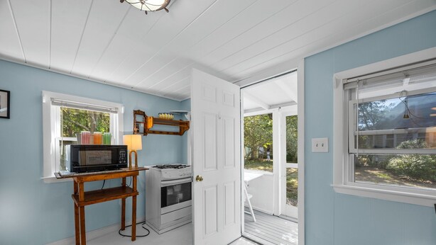 A kitchen with a stove, microwave, and a small table with a lamp. - Cozy pet-friendly 1-bedroom cottage near the beach in beautiful Truro with AC (Truro)