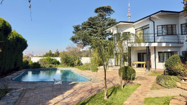 A modern two-story house with a swimming pool, a balcony, and a view of a tall tower. - Room-single Rooms With Shared Bathroom 2 (Johannesburg)