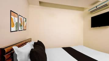Een hotelkamer met een bed, een flatscreen televisie aan de muur en twee kunstwerken in lijsten.