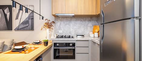 A modern kitchen with a built-in oven, a refrigerator, and a gas stove.